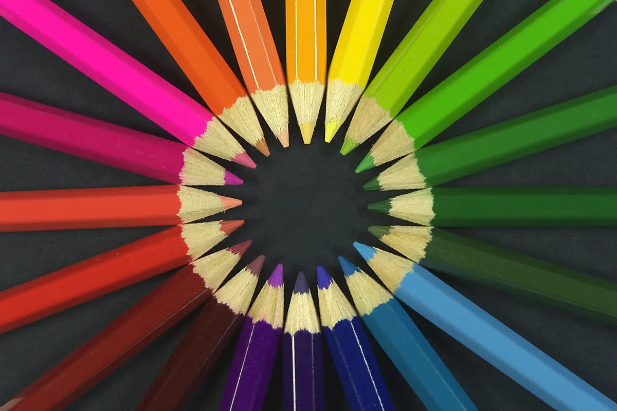 Coloured pencils arranged in a rainbow circle with sharpened tips