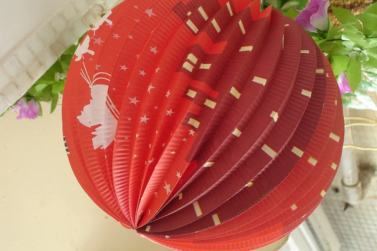 A close-up of a red paper honeycomb lantern decorated with stars and traditional motifs
