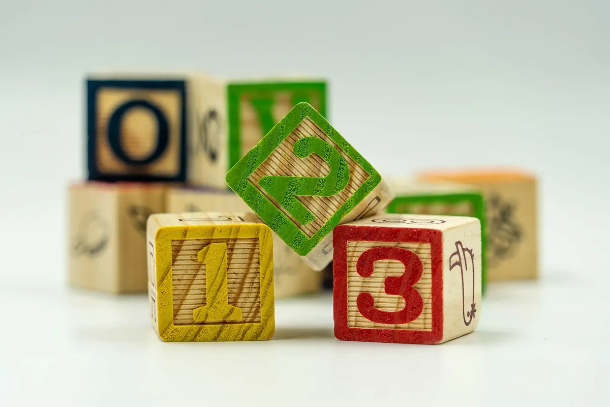 Wooden alphabet and number blocks stacked on a white background
